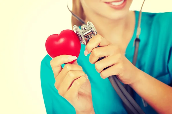 Vrouwelijke arts luistert via een stethoscoop naar het hart — Stockfoto