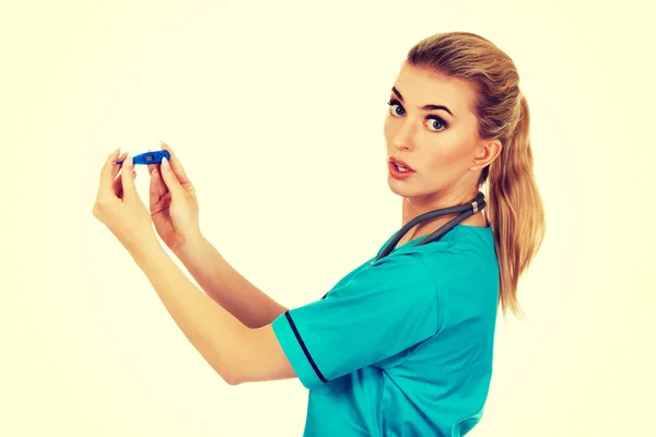 Suprised female nurse or doctor looking for thermometer — Stock Photo, Image