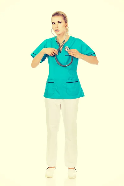 Junge Krankenschwester oder Ärztin hören ihr eigenes Herz — Stockfoto
