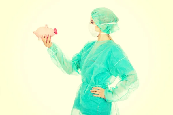 貯金箱を持って女性外科医医師 — ストック写真