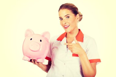 Young beautiful female doctor or nurse holding a piggybank clipart
