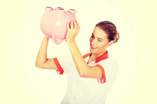 Young beautiful female doctor or nurse holding a piggybank — Stock Photo, Image