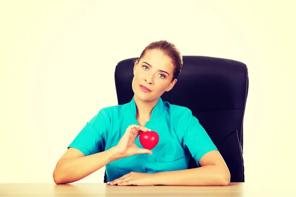 Giovane medico femminile che tiene il cuore giocattolo — Foto Stock