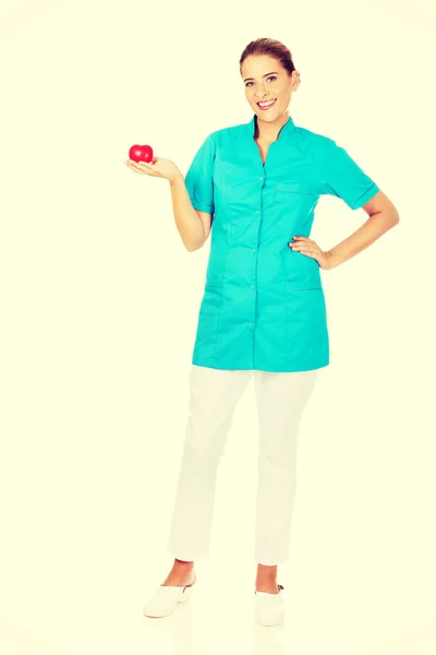 Young female doctor or nurse holding heart toy — Stock Photo, Image