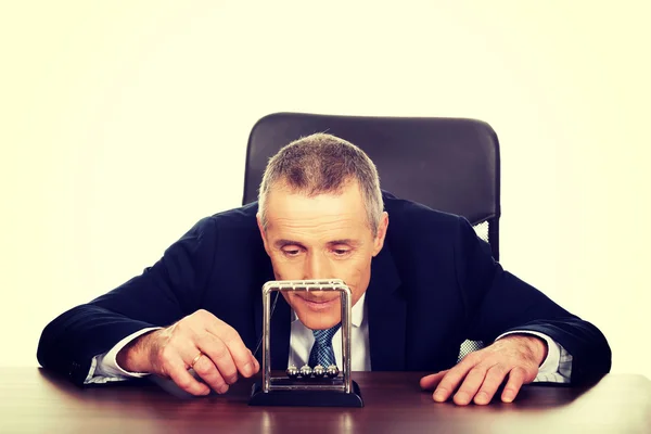 Empresário no escritório brincando com bolas de newton — Fotografia de Stock