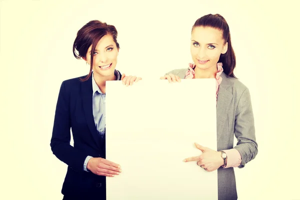 Két üzletasszonyok, kezében egy nagy fehér táblára. — Stock Fotó