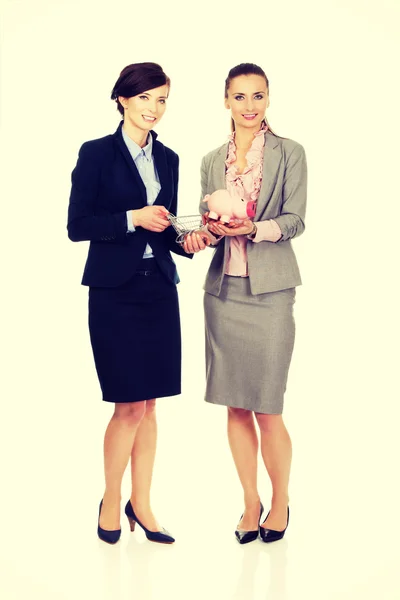 Duas mulheres de negócios com banco porquinho . — Fotografia de Stock