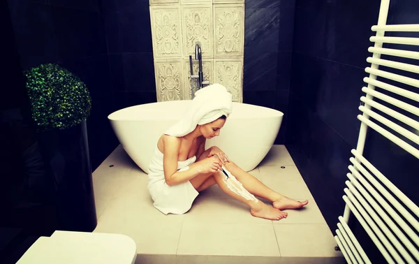 Frau rasiert sich das Bein. — Stockfoto