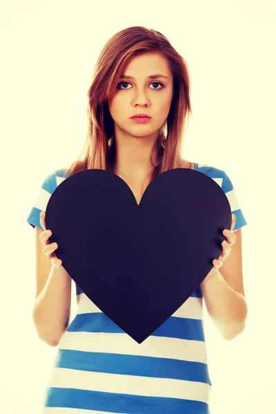 Worried teenage woman holding black paper heart — Stock Photo, Image