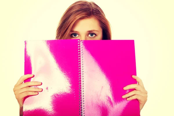 Teenage woman hiding her face behind a notebook — Stock Photo, Image