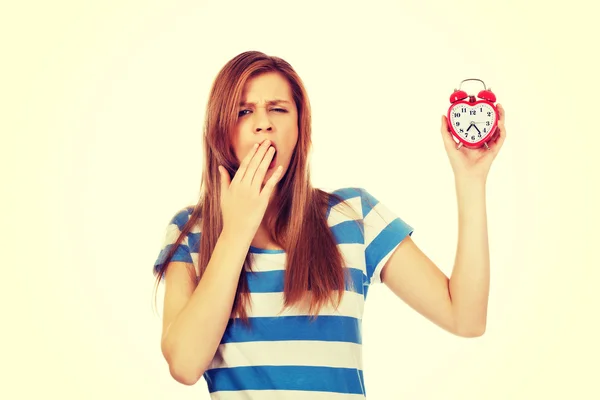 Yawning teenage woman holding alarm clock — Stock Photo, Image
