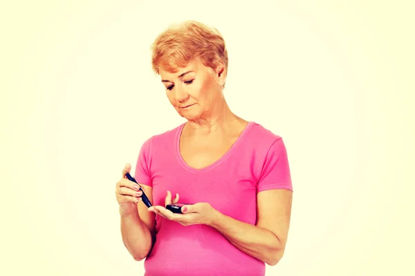 Senior woman with glucometer checking blood sugar level — Stock Photo, Image