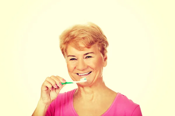 Mujer mayor sonriente cepillándose los dientes —  Fotos de Stock