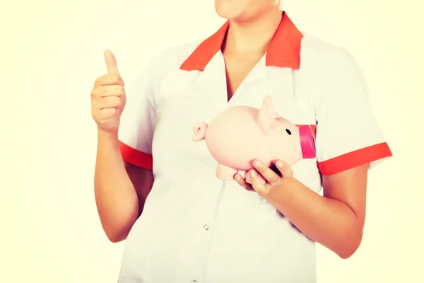 Young beautiful female doctor or nurse holding a piggybank — Stock Photo, Image