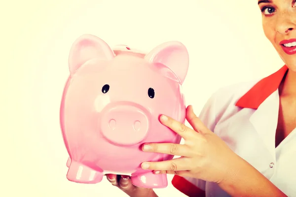 Young beautiful female doctor or nurse holding a piggybank — Stock Photo, Image