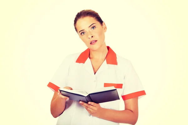 Jovem foco médico ou enfermeiro feminino faz anotações — Fotografia de Stock
