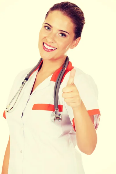 Jovem sorriso feminino médico ou enfermeira mostra polegar para cima — Fotografia de Stock