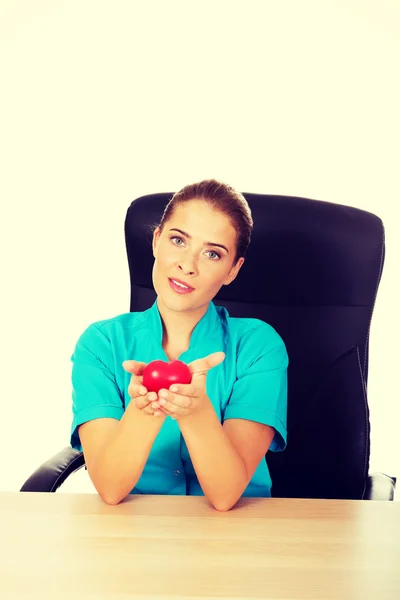 Young female doctor holding toy heart — Stock Photo, Image