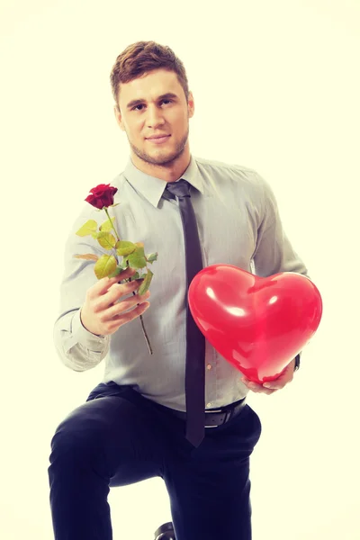 Hombre arrodillado con rosa roja y globo del corazón . — Foto de Stock