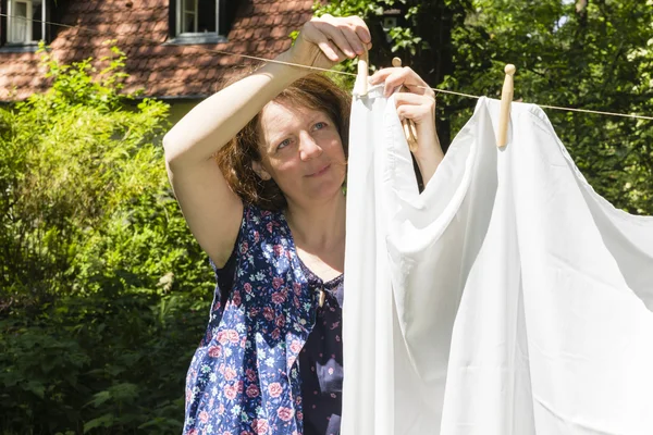 Frau beim W=scheaufh=ngen im Garten, pendurando a lavagem em — Fotografia de Stock