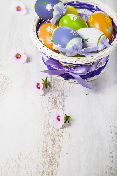 Ovos de Páscoa em uma cesta e flores — Fotografia de Stock