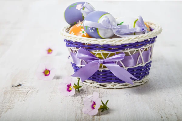 Easter eggs in a basket and flowers — Stock Photo, Image