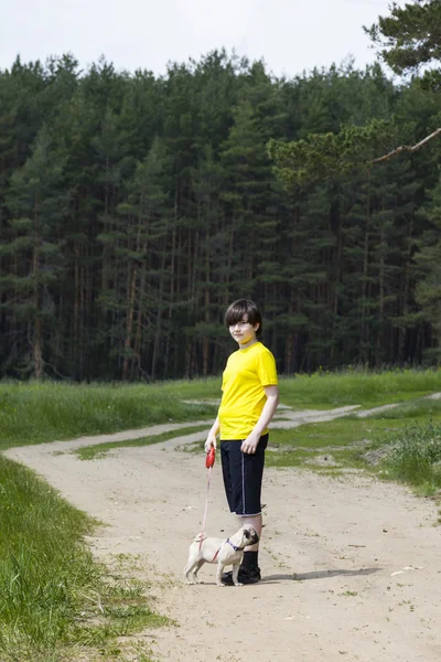 Boy walking with a dog near the forest — Stock Photo, Image