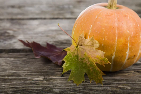 Pumpkins and fall leaves on a wooden table — Stock Photo, Image