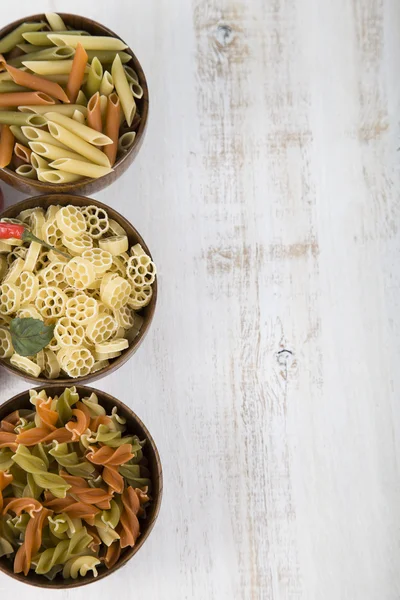 Raw pasta and spices in wooden bowls — Stock Photo, Image