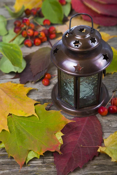 Lantern and fall leaves on an old wooden table — Stock Photo, Image