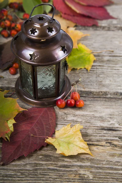 Lantern and fall leaves on an old wooden table — Stock Photo, Image