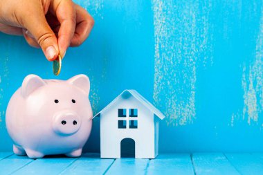 Kadın eli domuz kumbarasına bozuk para koyar. Gayrimenkul için tasarruf.