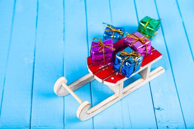 Mavi ahşap arka planda hediyeli kızaklar. Noel hediyeleri.