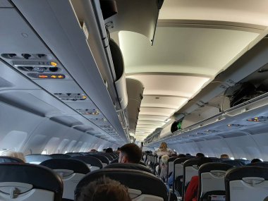 Uçaktaki insanlar uçuş için hazırlanıyorlar. Bagaj bölmeleri açık. Uçaktaki yolcular.