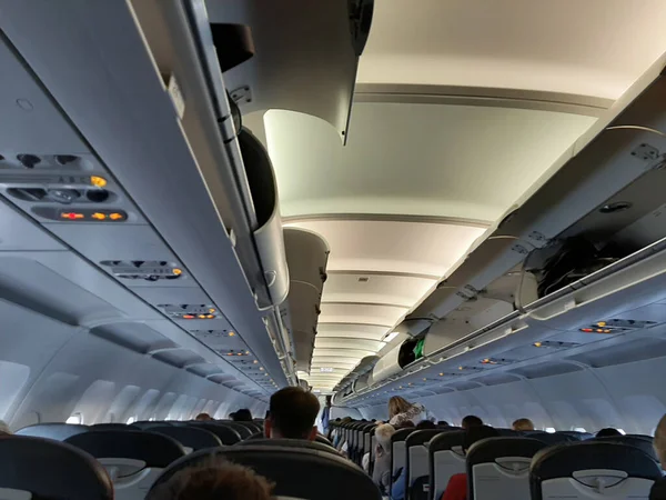 Uçaktaki insanlar uçuş için hazırlanıyorlar. Bagaj bölmeleri açık. Uçaktaki yolcular.