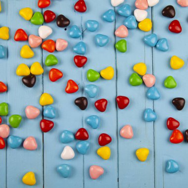 Mavi ahşap arka planda kalp şeklinde çok renkli şekerler. Sevgililer Günü. 