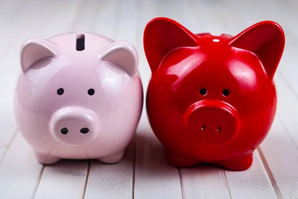 Pink and red pig piggy bank on a white wooden background. Accumulation of money.