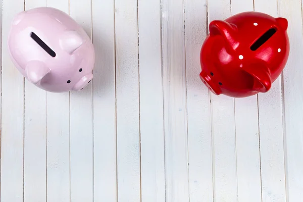 Two pigs piggy banks on a white wooden background, top view. Accumulation of money.