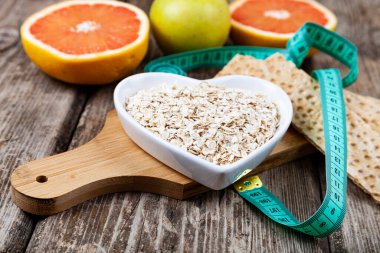 Yararlı ürünler, mezura, yulaf ezmesi ve ahşap arka planda dambıllar. Diyet ve sağlıklı yaşam tarzı.