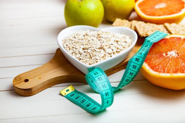 Yararlı ürünler, mezura, yulaf ezmesi ve ahşap arka planda dambıllar. Diyet ve sağlıklı yaşam tarzı.