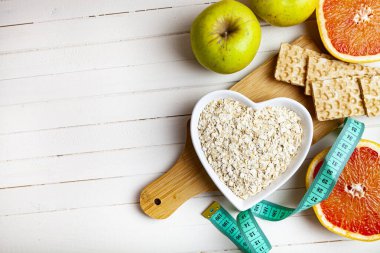 Yararlı ürünler, mezura, yulaf ezmesi ve ahşap arka planda dambıllar. Diyet ve sağlıklı yaşam tarzı.