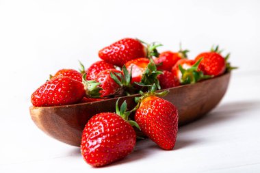 Ahşap bir arka planda ahşap bir kasede olgun çilekler..