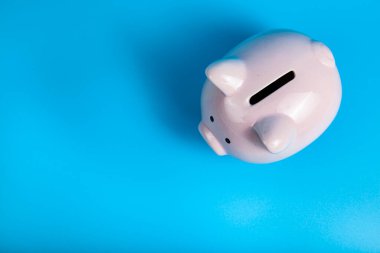 Mavi arka planda pembe domuz kumbarası. Para birikimi.