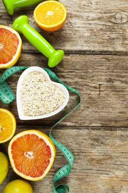 Yararlı ürünler, mezura, yulaf ezmesi ve ahşap arka planda dambıllar. Diyet ve sağlıklı yaşam tarzı.