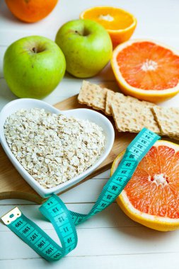 Yararlı ürünler, mezura, yulaf ezmesi ve ahşap arka planda dambıllar. Diyet ve sağlıklı yaşam tarzı.