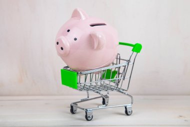 Alışveriş arabasında domuz kumbarası. Para biriktirme kavramı.