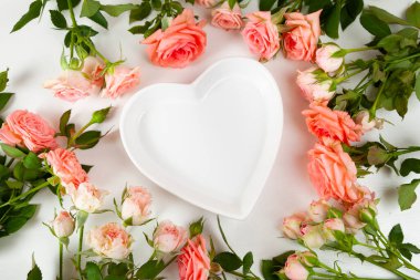 Çiçekler ve tahta bir arka planda kalp şeklinde bir tabak. Güllü güzel tebrik kartı.