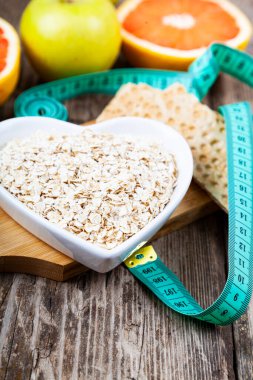 Yararlı ürünler, mezura, yulaf ezmesi ve ahşap arka planda dambıllar. Diyet ve sağlıklı yaşam tarzı.