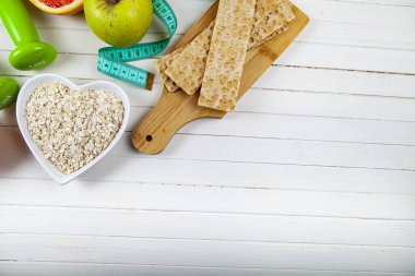 Yararlı ürünler, mezura, yulaf ezmesi ve ahşap arka planda dambıllar. Diyet ve sağlıklı yaşam tarzı.