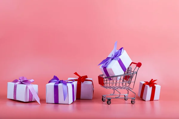 ピンクの背景にショッピングカートやギフト コンセプト 贈り物の購入 — ストック写真